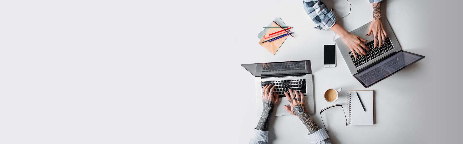 Overhead view of desk with computers and hands